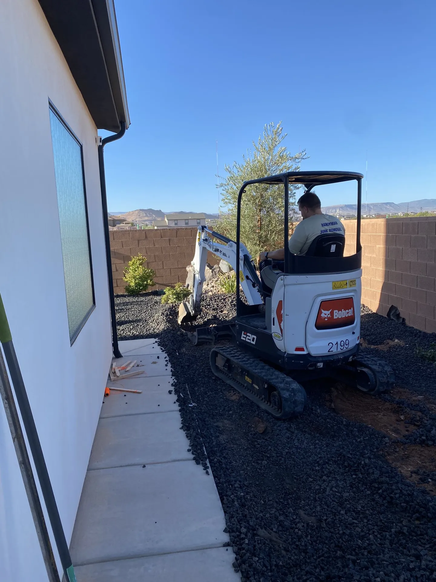 Viking Solutions shed build in St. George — Bobcat E20 excavator during site prep with red rock mountains in background
