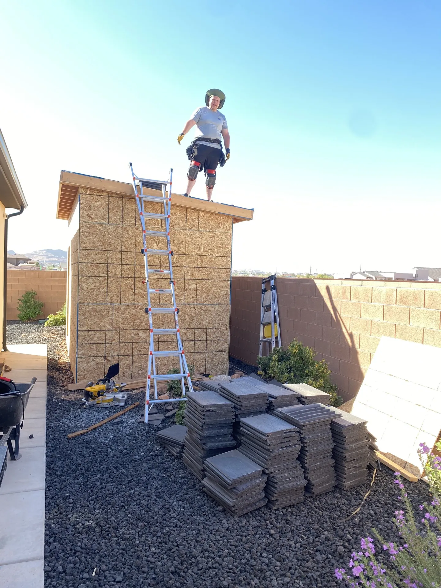 Viking Solutions shed build — crew member standing on finished roof deck with tile stacks ready to install