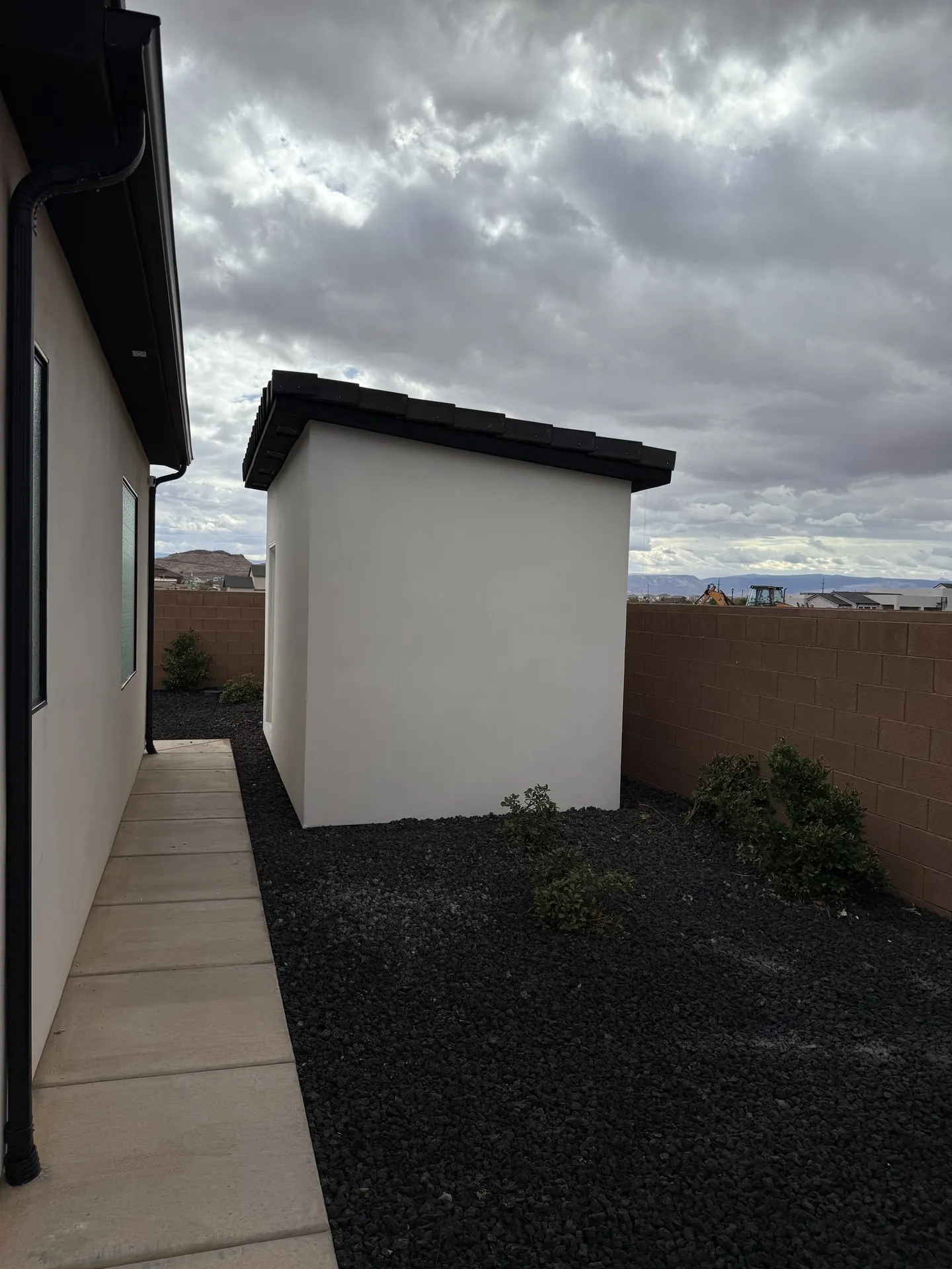 Viking Solutions shed build exterior side view — white stucco, dark tile roof, red rock mountains in background
