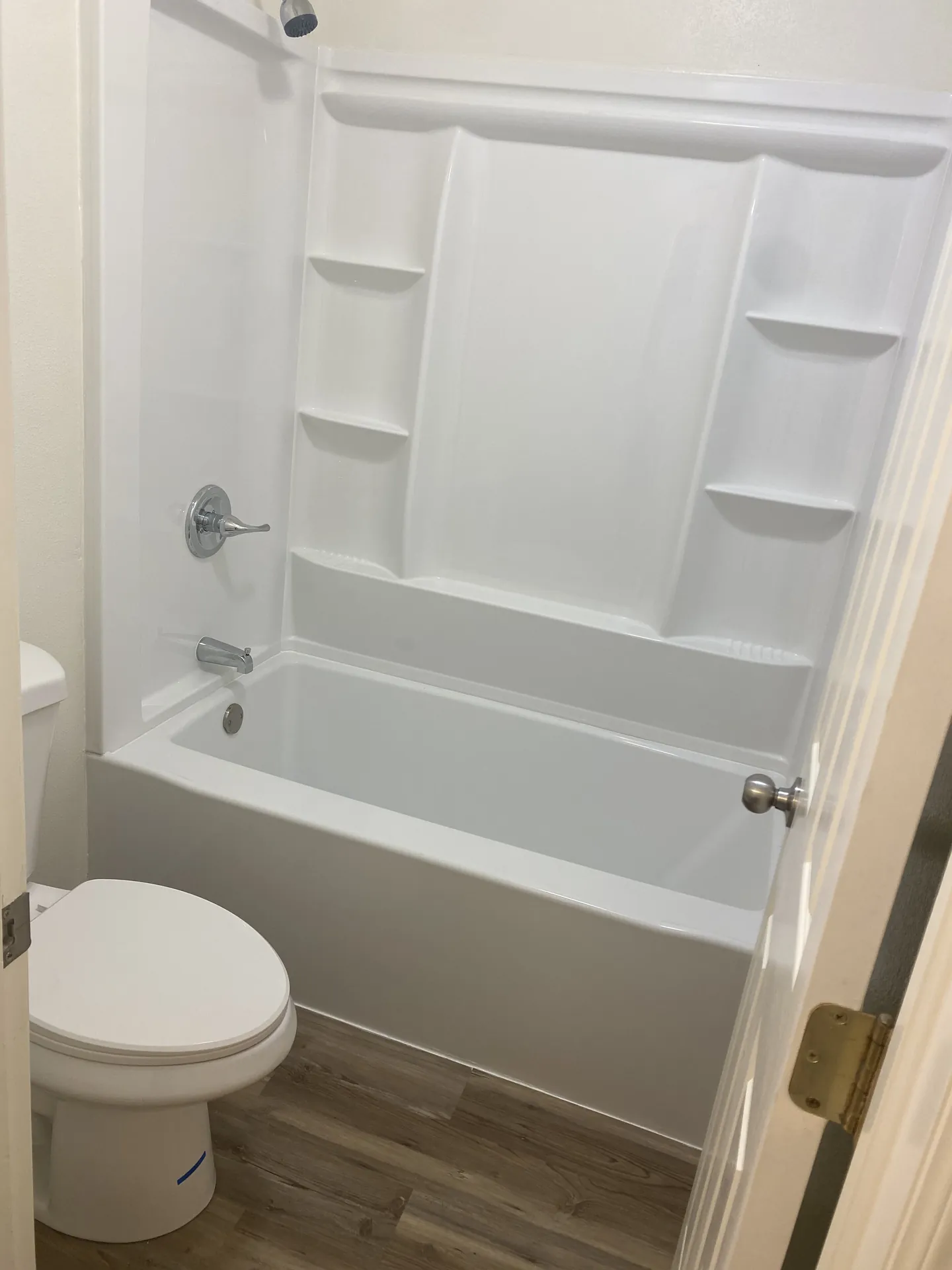 Finished bathroom with new white tub/shower combo, chrome fixtures, and new toilet