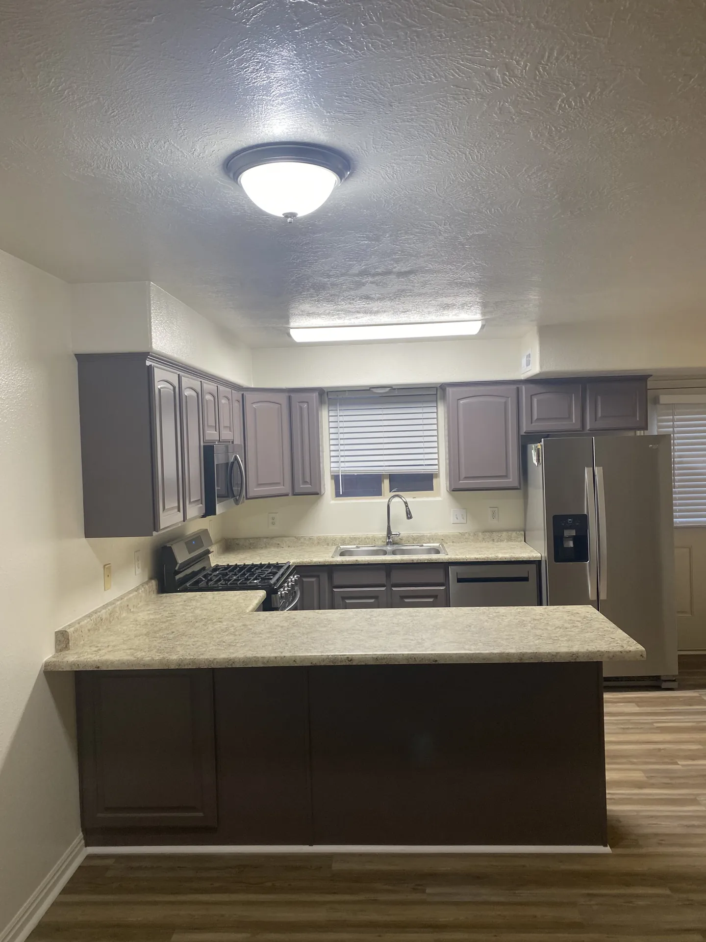 Wide shot of finished kitchen showing full cabinet layout and new LVP flooring