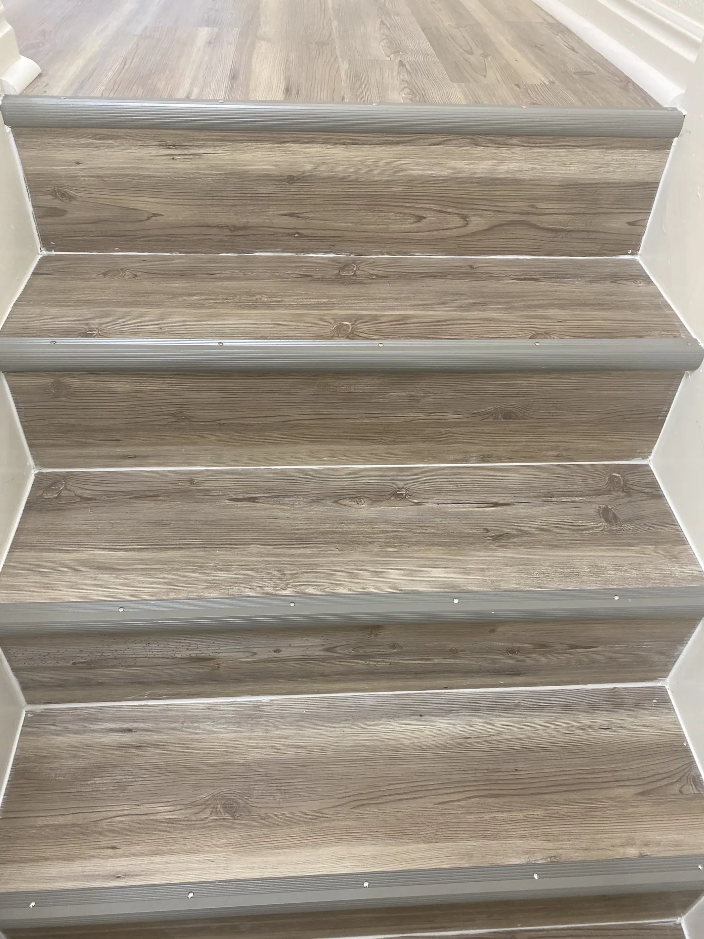New LVP flooring installed on stairs with aluminum stair nosing — clean finished detail