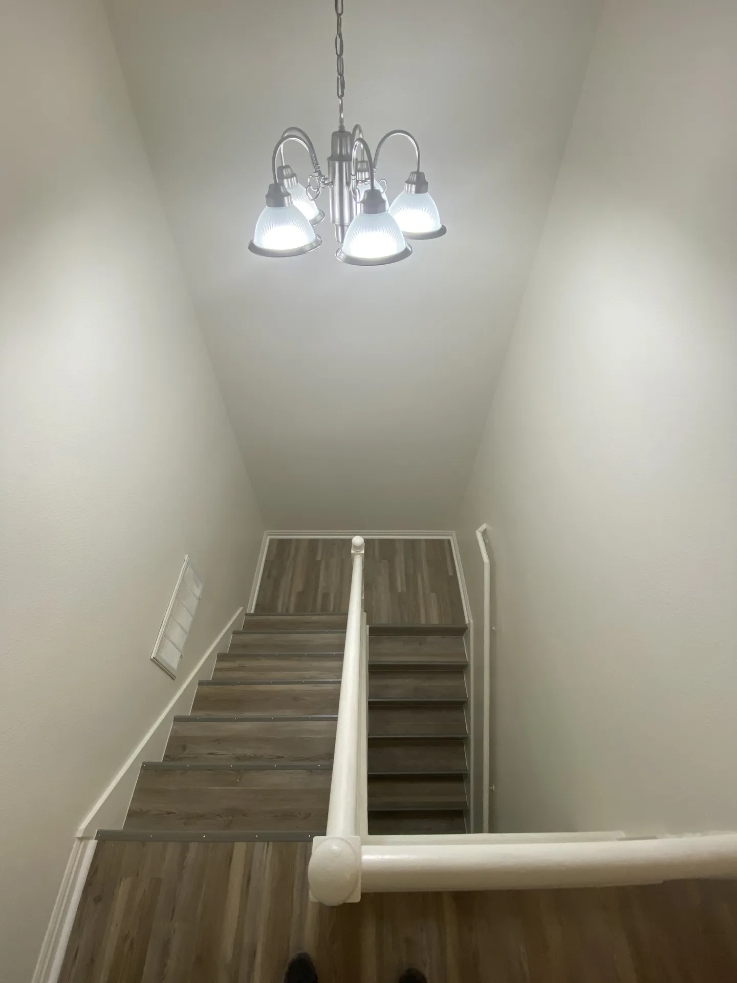Finished stairwell with new chandelier light fixture and new LVP on stairs