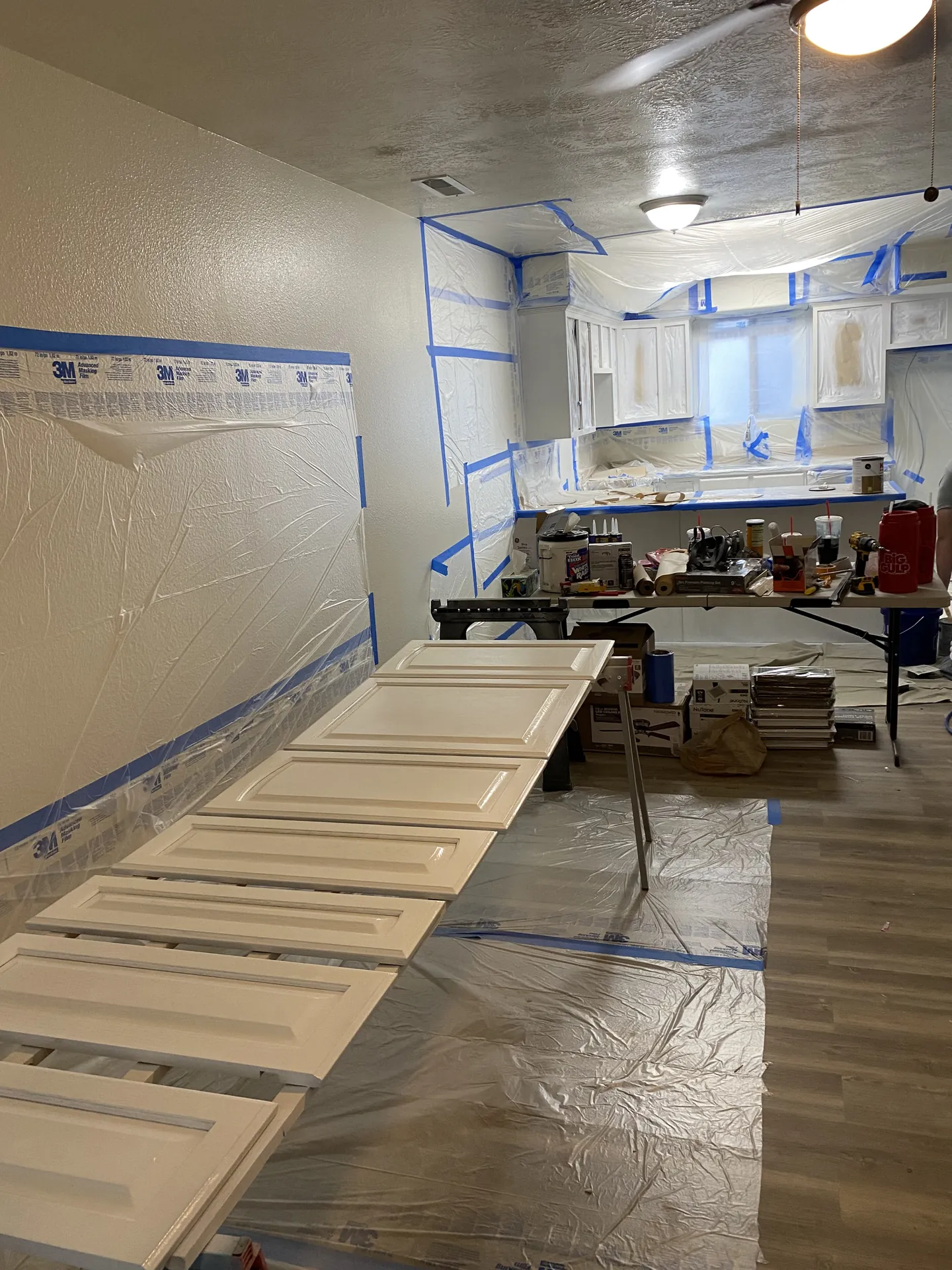 Cabinet doors laid flat and freshly painted white, drying before reinstall