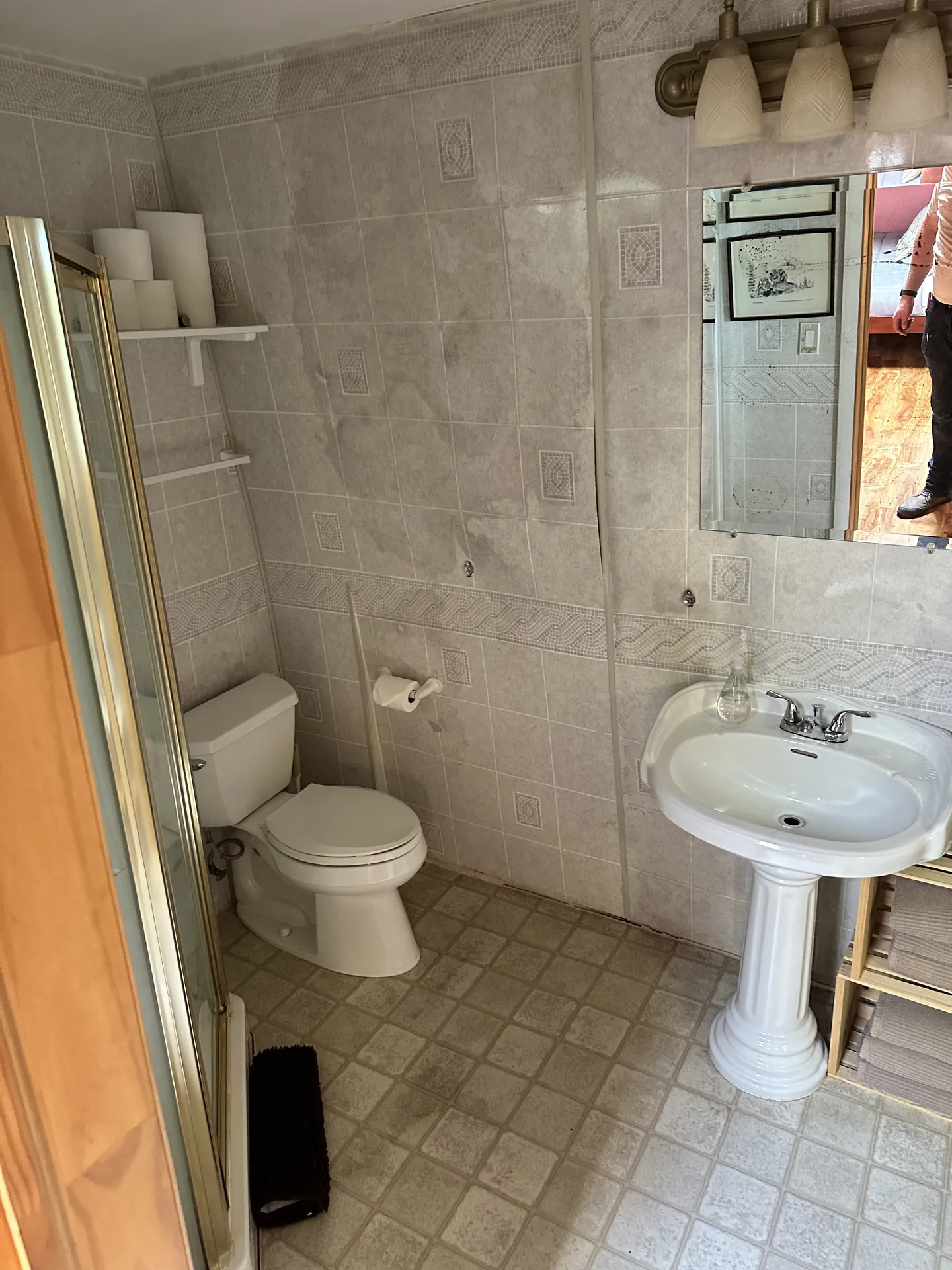 Bathroom before remodel — dated beige tile, pedestal sink, gold-frame shower door, 1990s fixtures