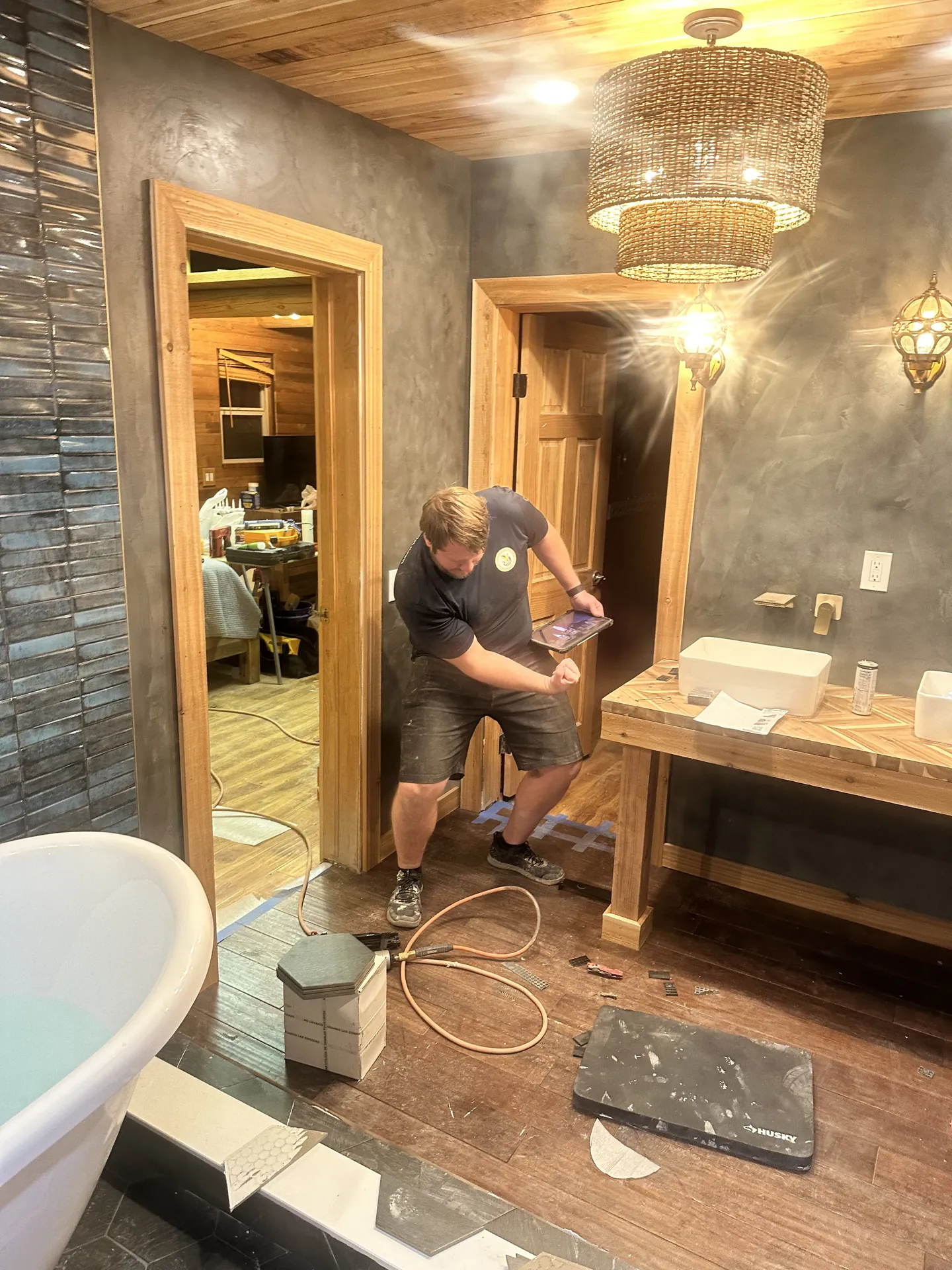 Bathroom remodel progress — vanity area from second angle, worker visible, showing the design coming together