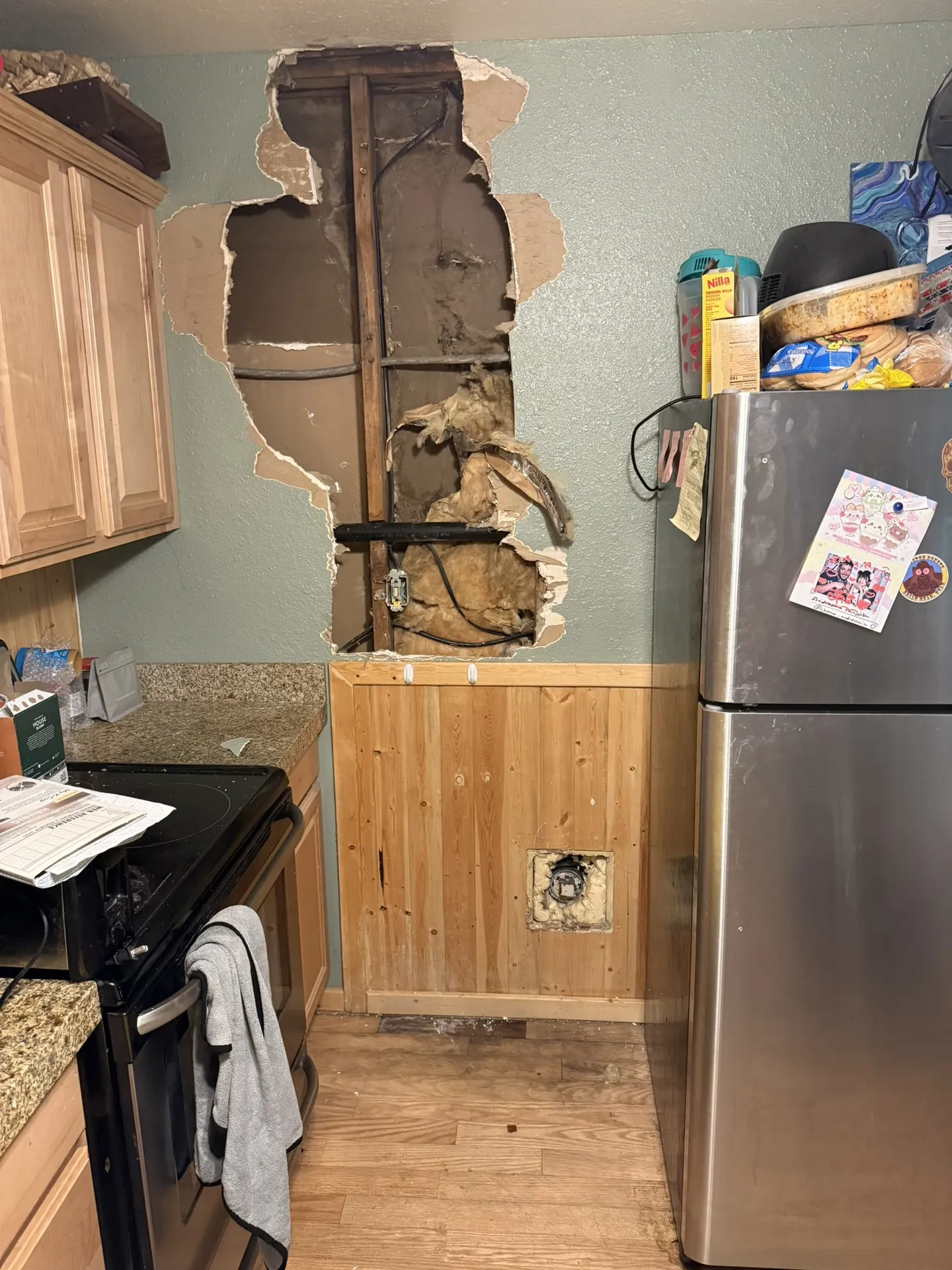 Kitchen wall damage in Brian Head Utah cabin — large hole through drywall exposing studs, insulation, and wiring