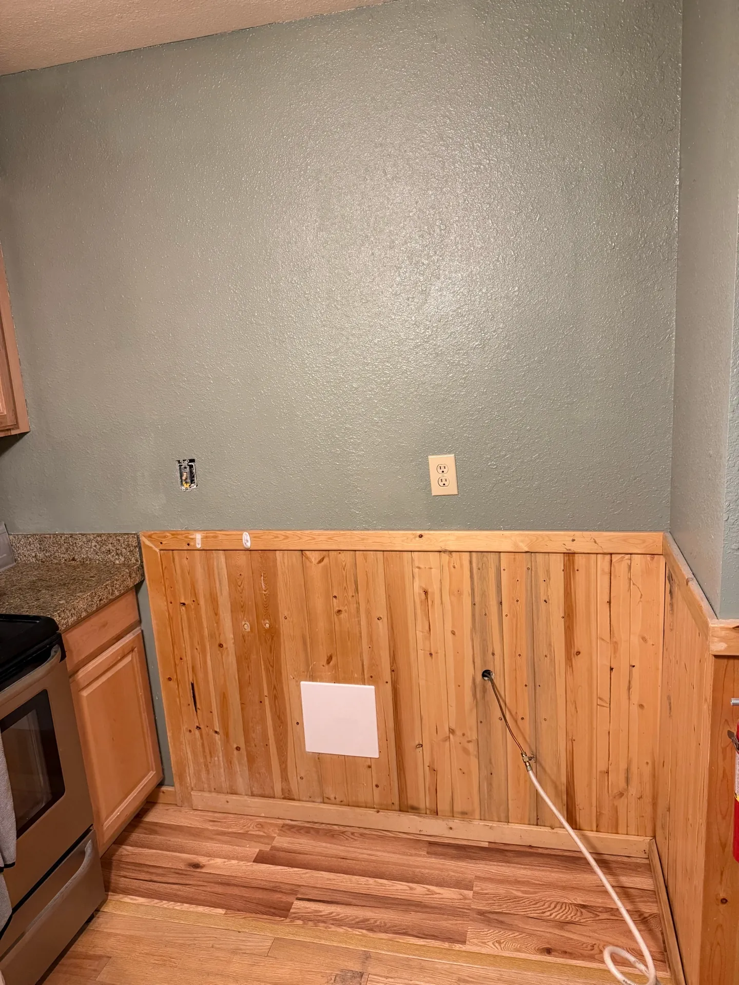 Brian Head kitchen repair — wider view showing full wainscoting rebuild and painted wall with outlets restored