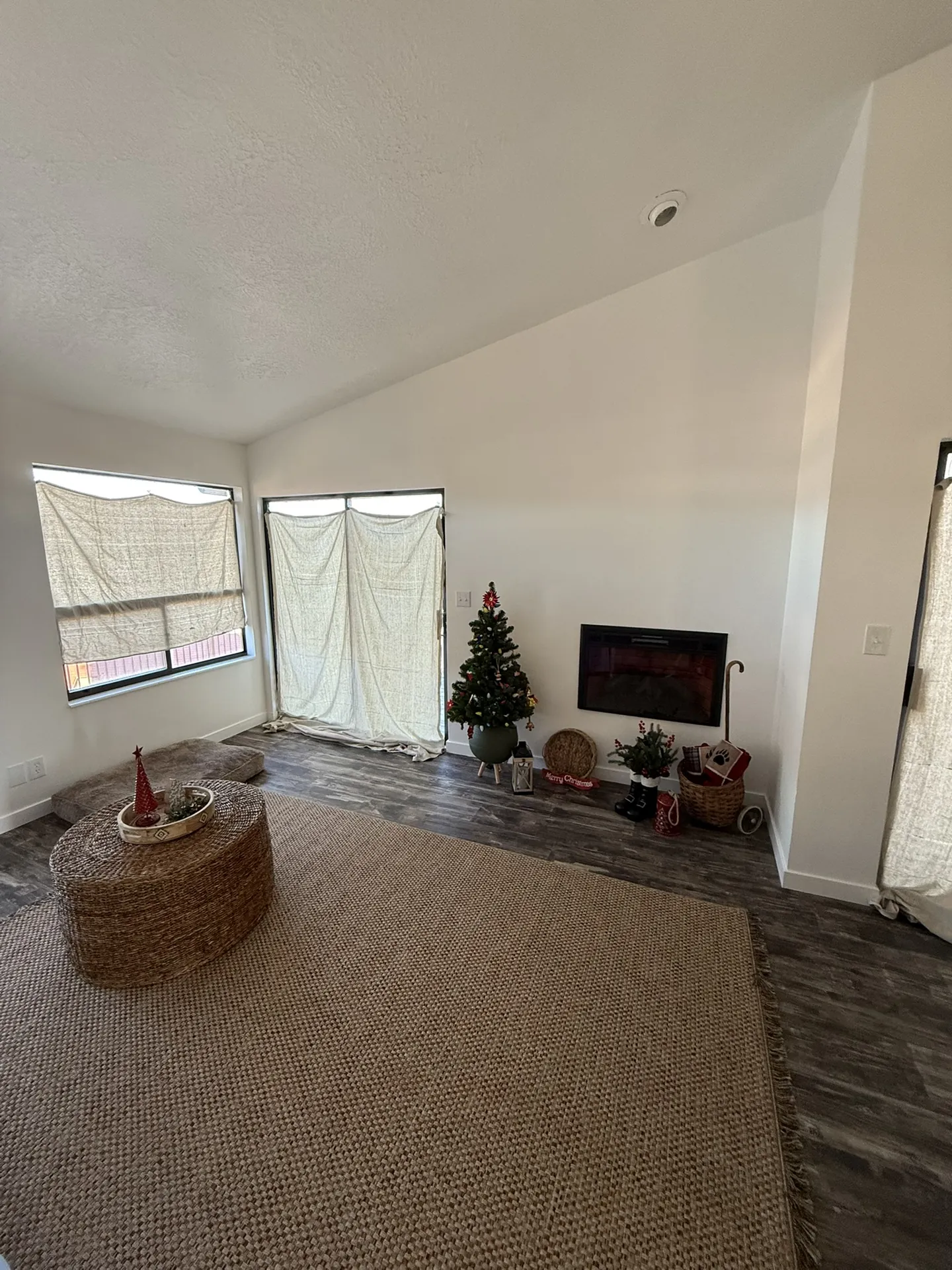 Condo after remodel — living room with new dark LVP floors, wall-mounted fireplace, vaulted ceiling, and new lighting