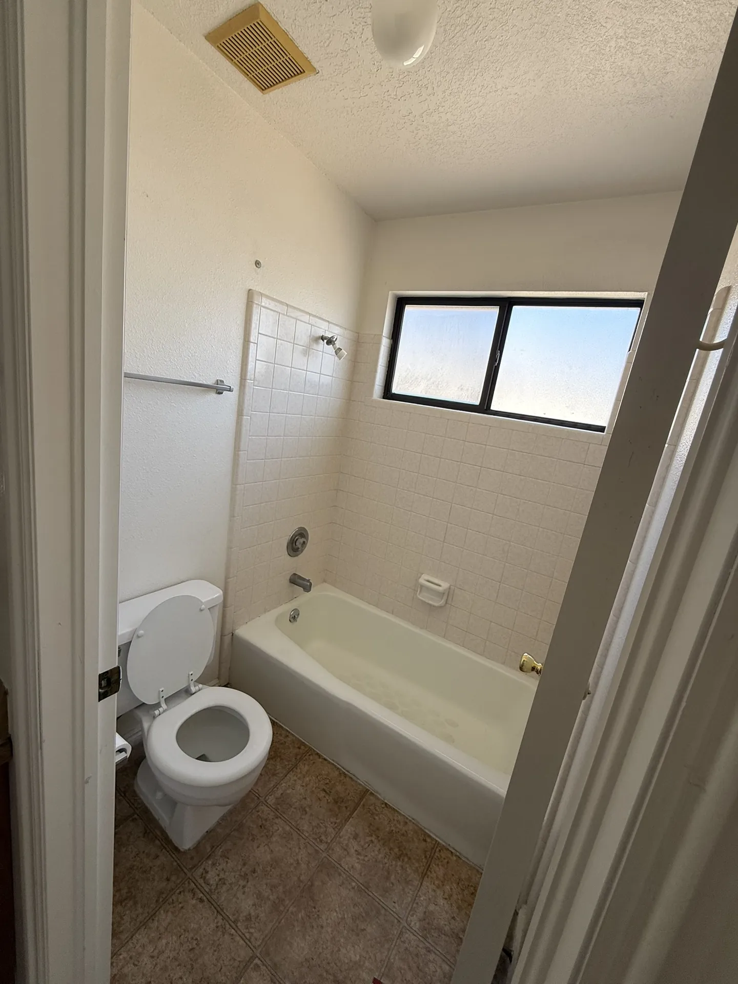 Condo before remodel — hall bathroom with original tub surround tile, old vanity, and dated fixtures