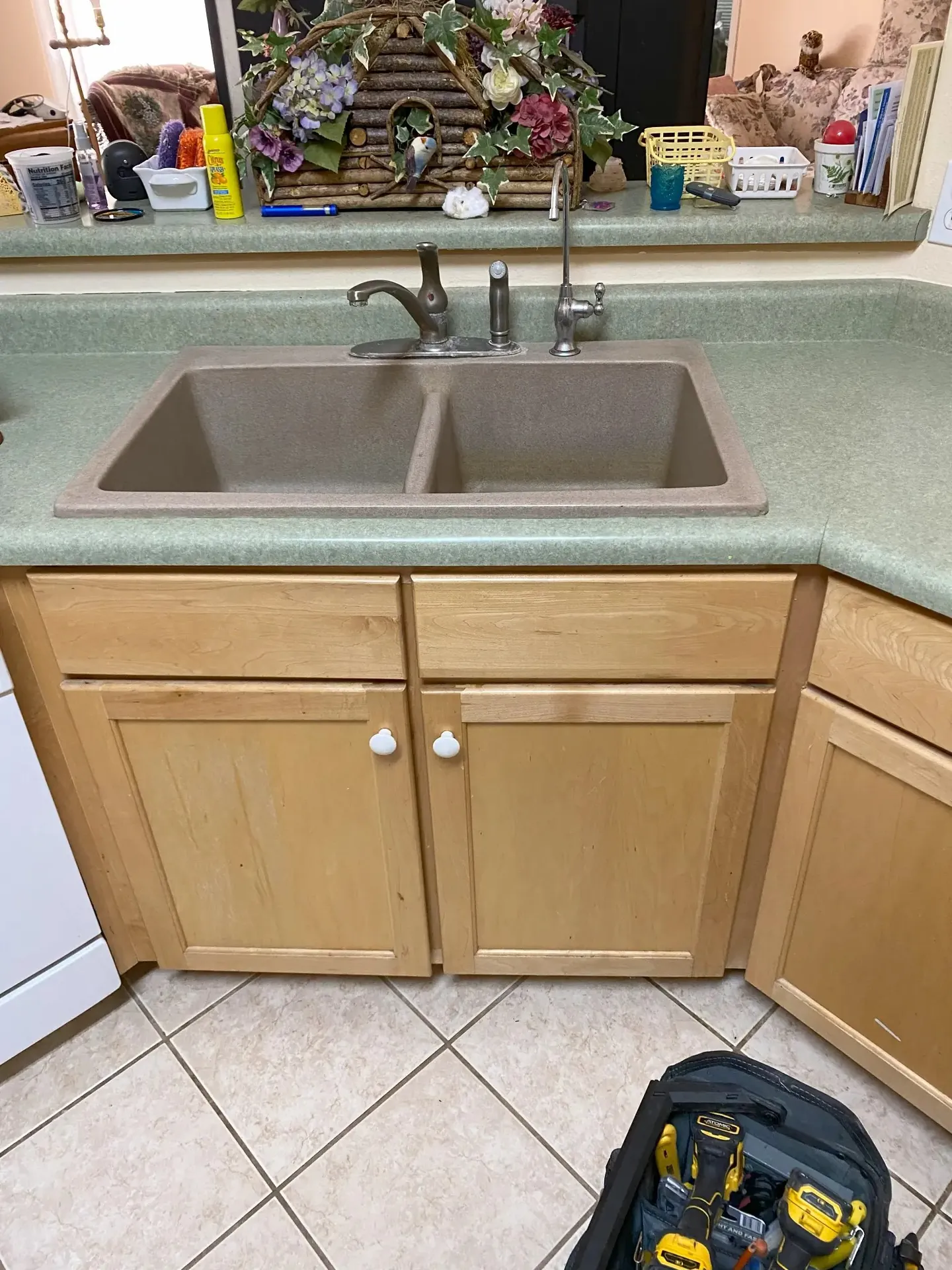 Kitchen sink before faucet replacement — old taupe composite sink, dated brushed nickel faucet, Viking tool bag on floor