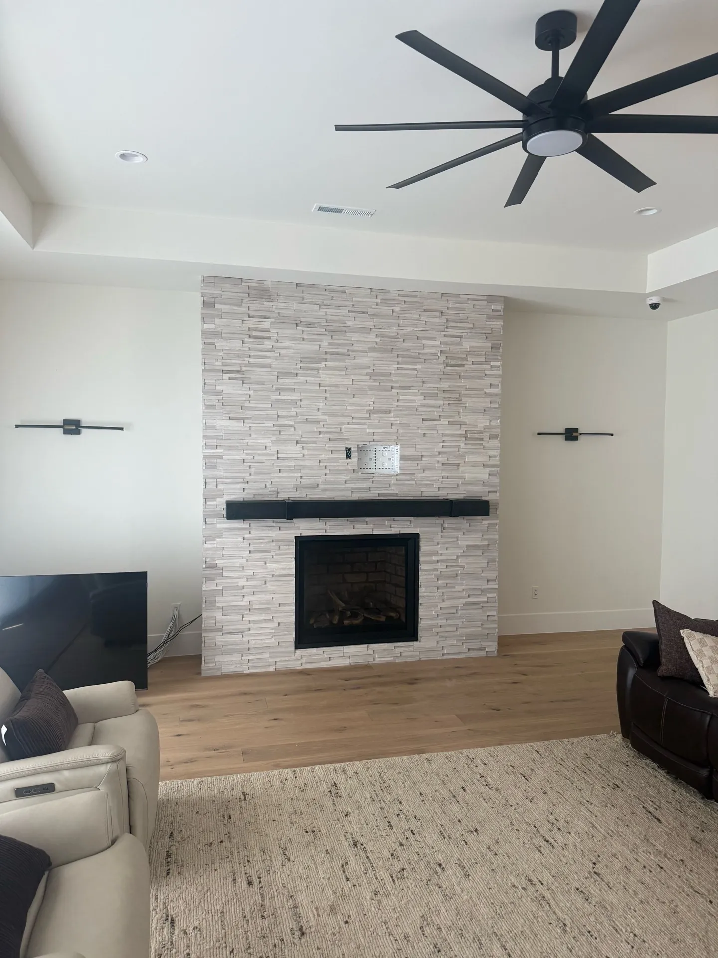 Modern ledger stone fireplace wall with black floating mantel in bright living room