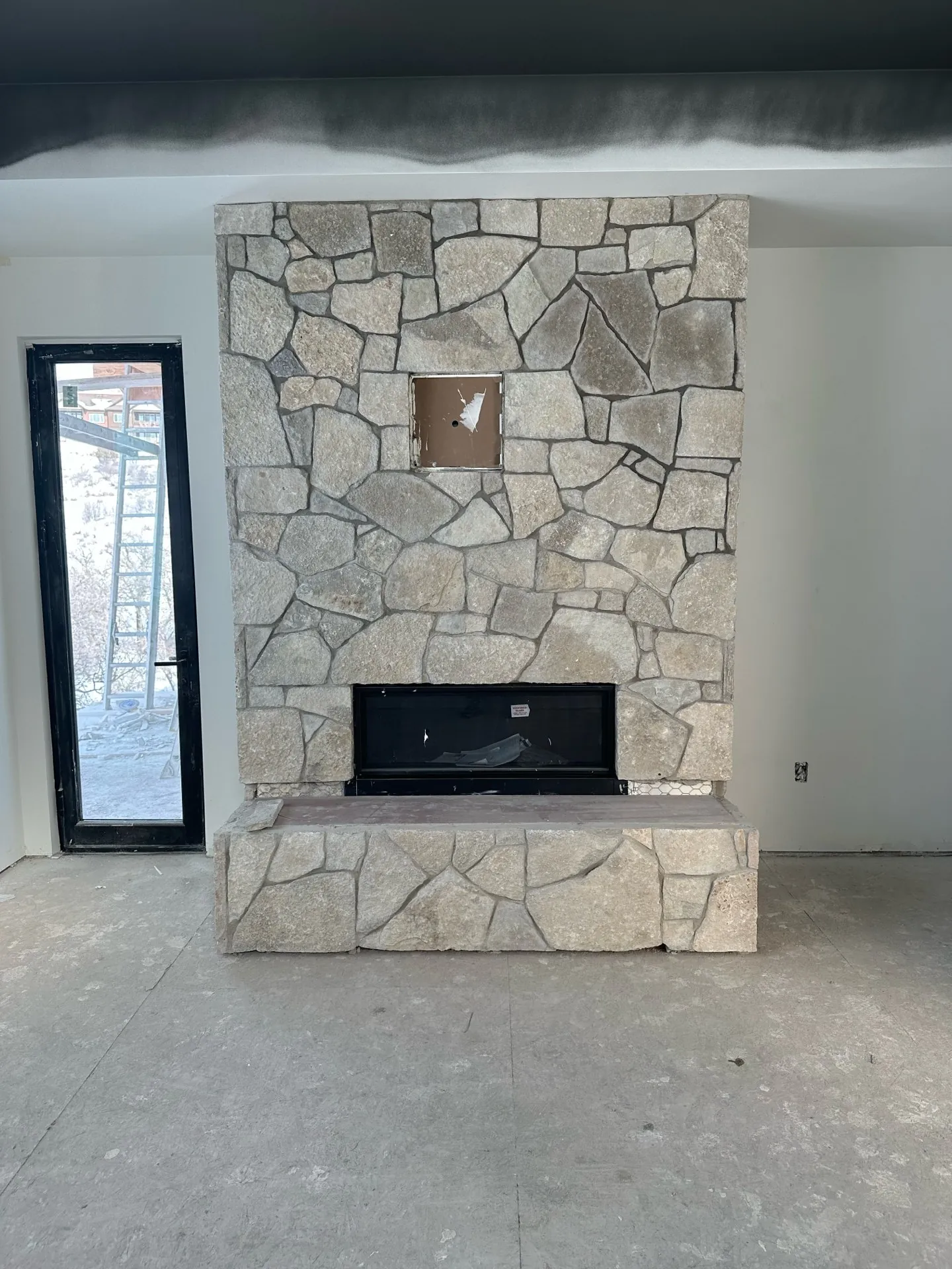 Hand-set natural stone fireplace wall in new construction home under construction