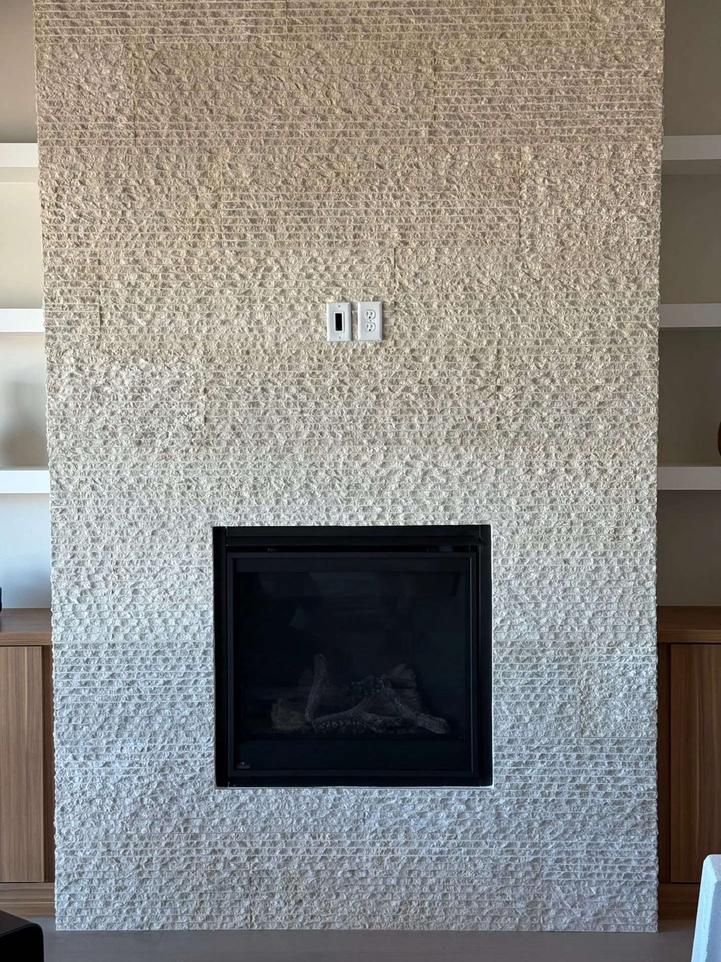 Split-face travertine tile fireplace wall in modern home with gas fireplace