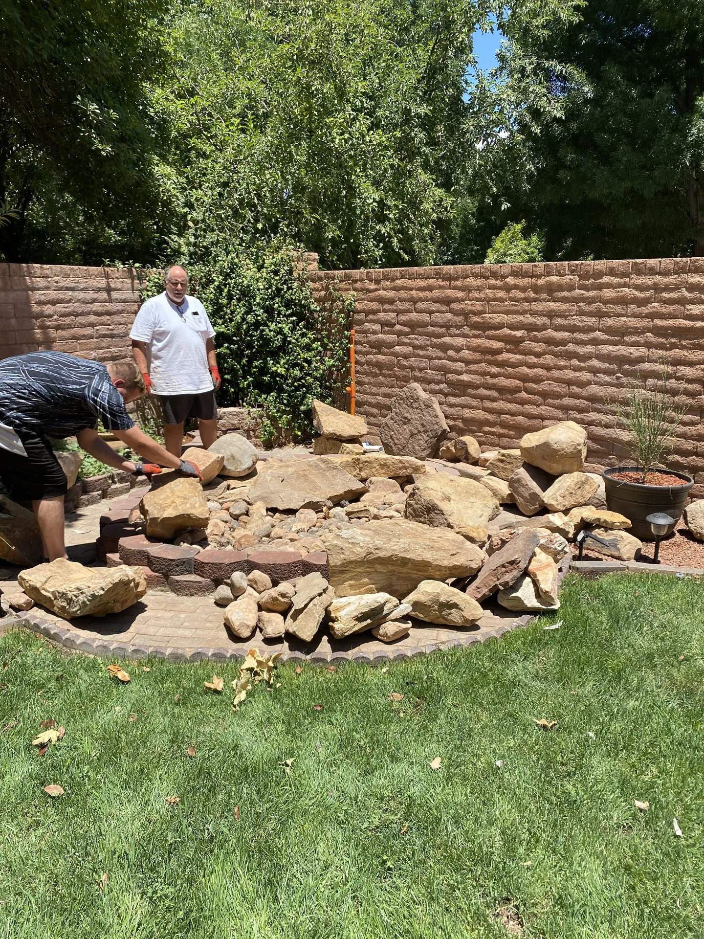 Viking Solutions crew actively placing and arranging large sandstone boulders on the circular paver pad during fountain construction