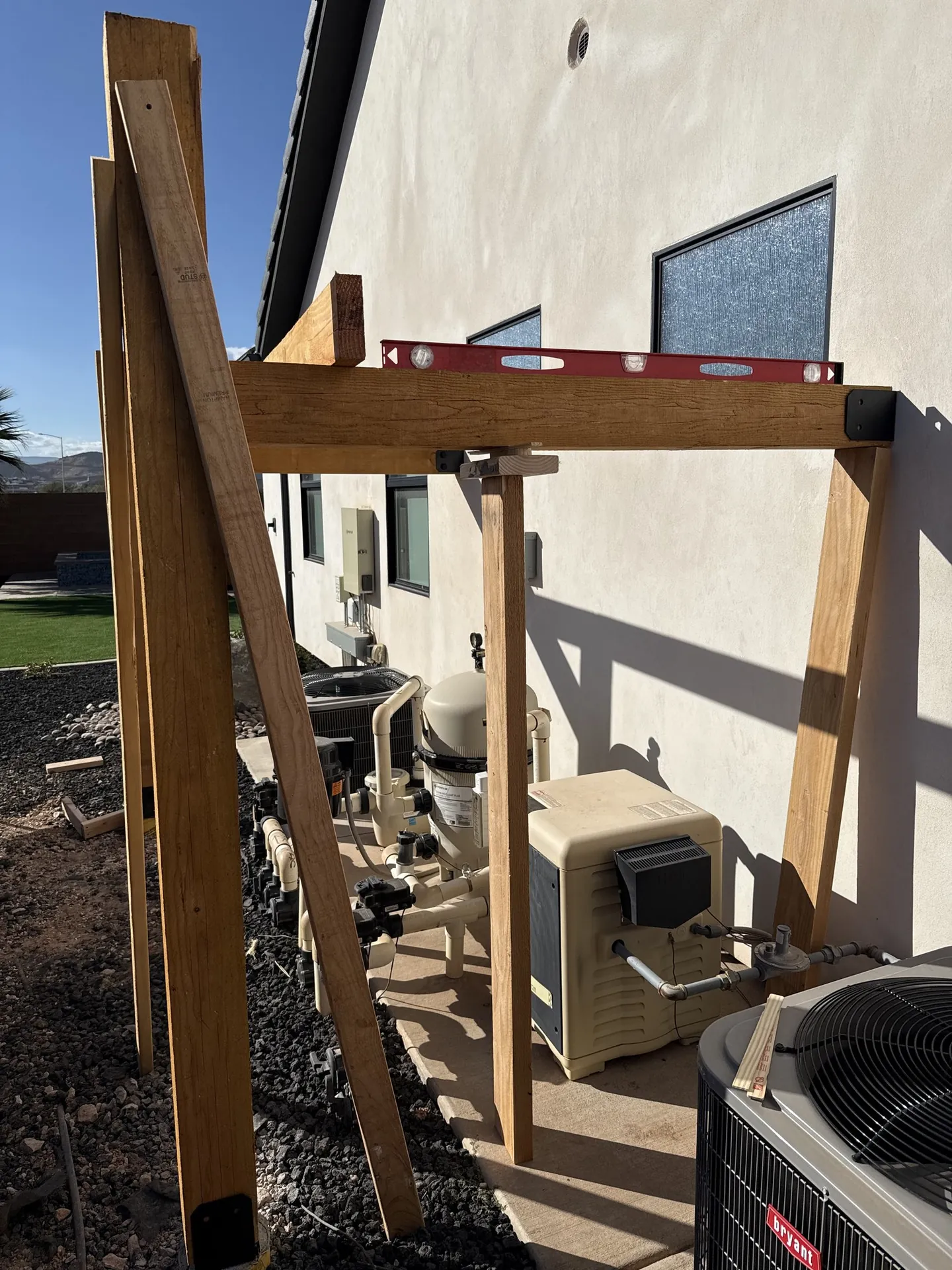 Finished pergola from alternate angle showing pool equipment underneath and clean post framing