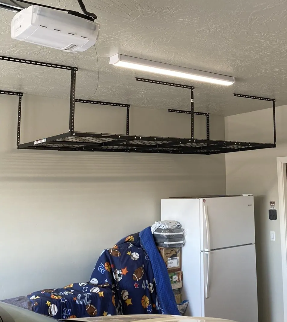 Garage after overhead storage rack installation — black steel ceiling-mounted rack anchored to joists