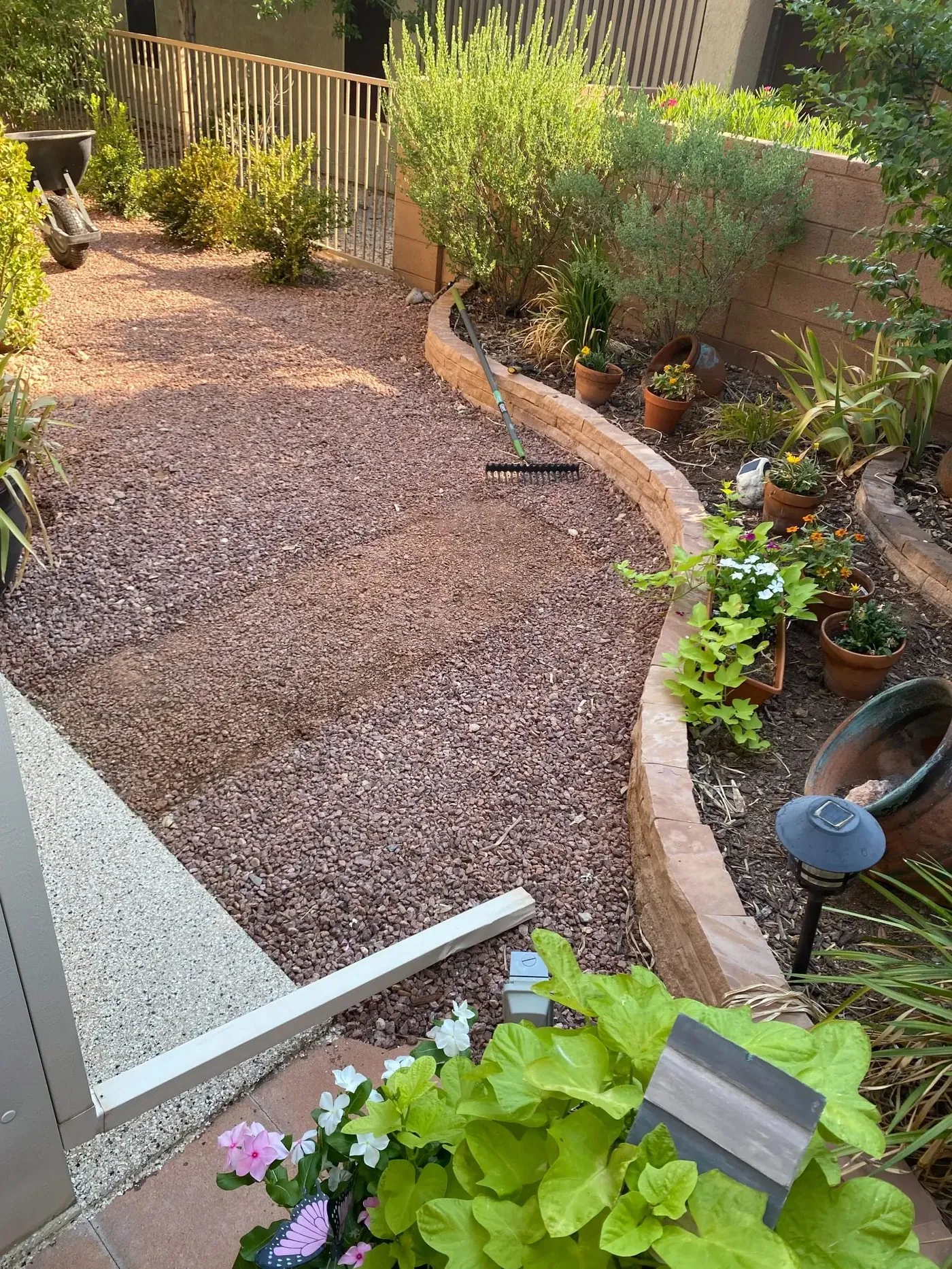 Before: gravel bed in St. George backyard before artificial turf installation — curved retaining wall border visible