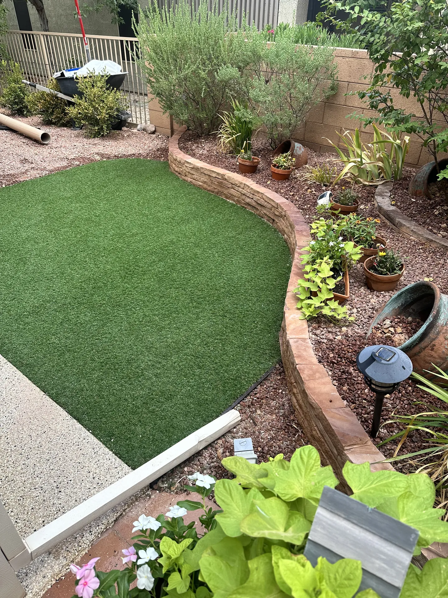 Artificial turf being laid in St. George backyard — turf freshly installed, curved retaining wall border visible