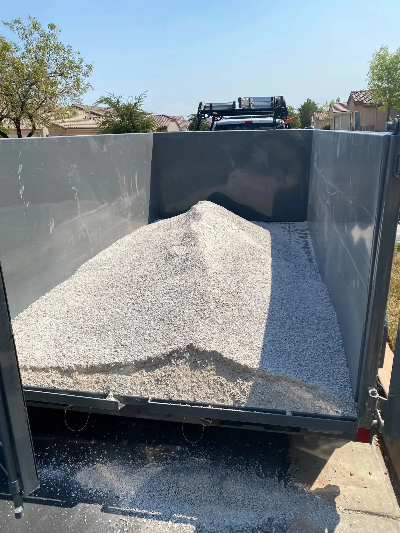 Trailer loaded with white decomposed granite being hauled away from St. George turf install site