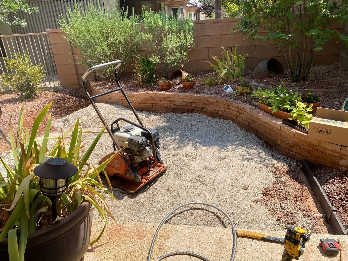 Plate compactor on freshly excavated base in St. George backyard — prep for artificial turf installation